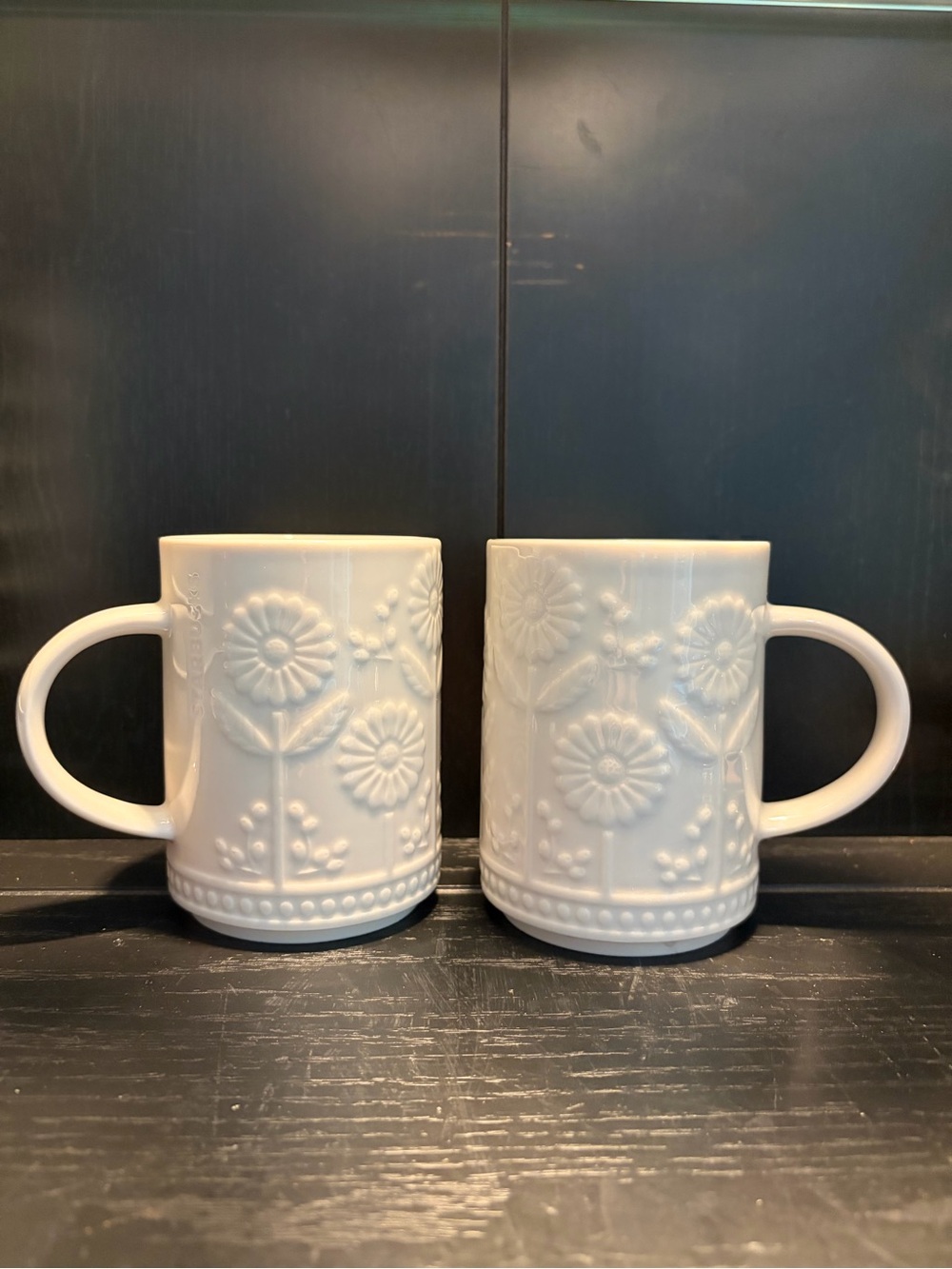 Two Starbucks 12 oz ceramic mugs with embossed daisy or sunflower floral design